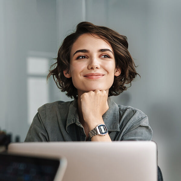 eine Frau sitzt lächelnd vor einem Laptop